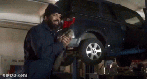 A Man Is Working On A Car In A Garage With A No Smog Sign In The Background GIF