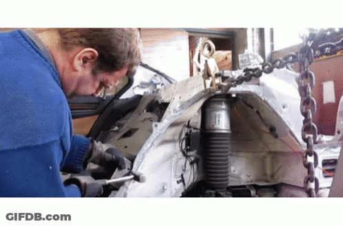 A Man Is Working On A Car With A Shock Absorber Attached To It GIF