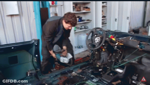 A Man Is Working On The Inside Of A Car With A Warning Sign In The Corner GIF