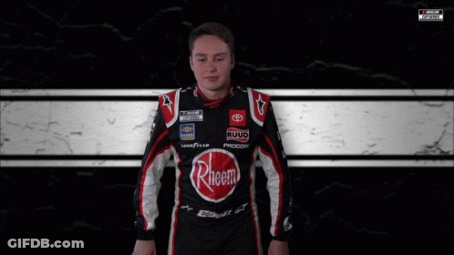 A Man Is Wrapped In A Black And White Checkered Blanket With A Nascar Logo In The Corner GIF