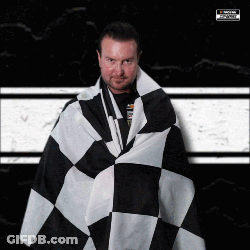 A Man Is Wrapped In A Black And White Checkered Flag With A Nascar Logo In The Background GIF