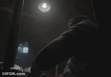 A Man Is Wrapped In Duct Tape And Sitting In A Chair In A Dark Room . GIF