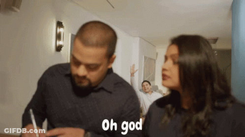 A Man Is Writing On A Piece Of Paper While A Woman Looks On And Says " Oh God " GIF