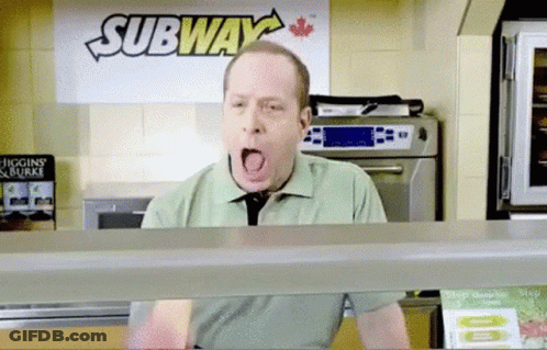 A Man Is Yawning In Front Of A Sign That Says Subway GIF