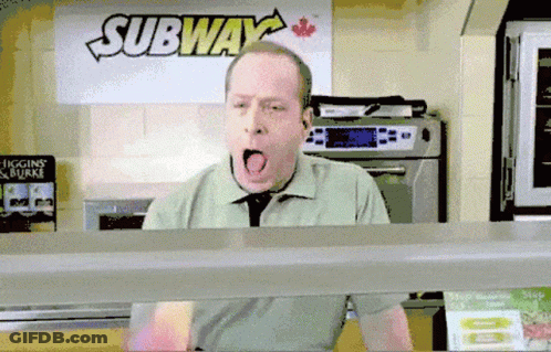 A Man Is Yawning In Front Of A Sign That Says Subway GIF