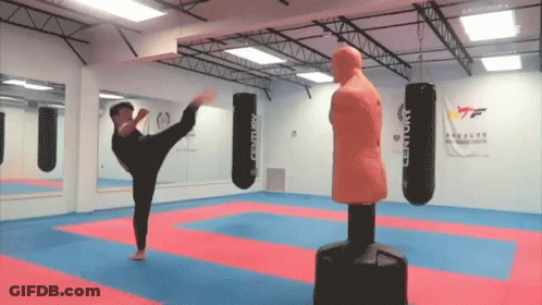 A Man Kicking A Century Boxing Bag In A Gym GIF