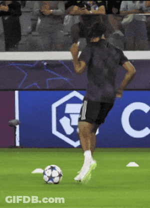 A Man Kicks A Soccer Ball In Front Of A Sign That Says Fc GIF