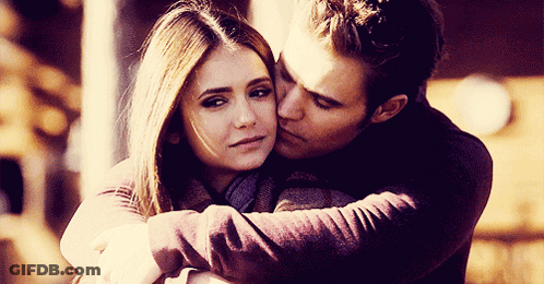A Man Kisses A Woman On The Forehead While They Hug GIF