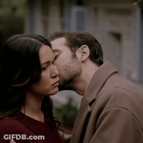 A Man Kissing A Woman On The Forehead In A Close Up GIF