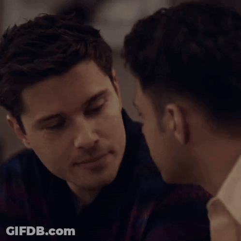 A Man Kissing Another Man On The Cheek In A Close Up GIF