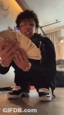 A Man Kneeling Down Holding A Stack Of Money GIF