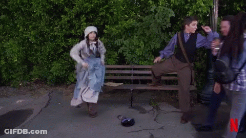 A Man Kneeling On A Bench Next To A Woman In A Blue Dress With A N On The Bottom GIF