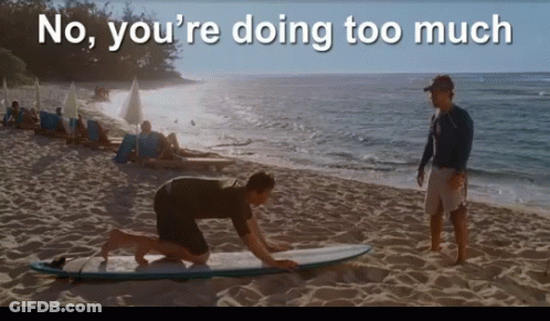 A Man Kneeling On A Surfboard On A Beach With The Words " No You 'Re Doing Too Much " GIF