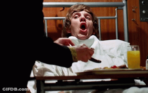 A Man Laying In A Hospital Bed With His Mouth Open And A Tray Of Food GIF