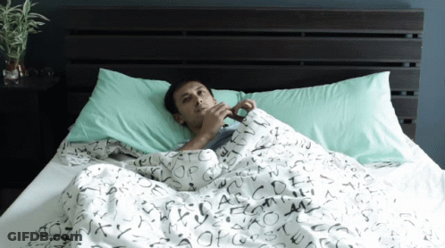 A Man Laying In Bed With A Blanket That Has The Letters Abcdefghijklmnopqrstuvwxyz Written On It GIF