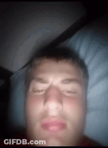 A Man Laying In Bed With His Eyes Closed And His Mouth Open GIF