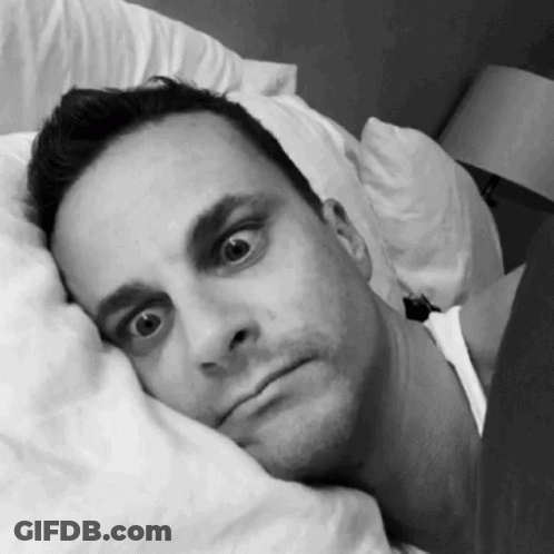 A Man Laying In Bed With His Head On A Pillow GIF