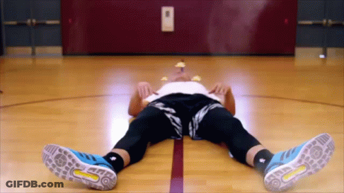 A Man Laying On A Basketball Court Wearing Blue Adidas Shoes GIF
