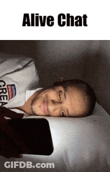 A Man Laying On A Bed Looking At A Cell Phone With The Words " Alive Chat " Above Him GIF