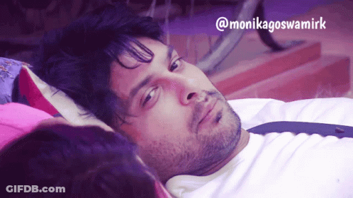 A Man Laying On A Bed Next To A Woman With The Name Monikagoswamirk On The Bottom Right GIF
