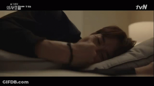 A Man Laying On A Bed With A Tvn Logo On The Bottom Right GIF
