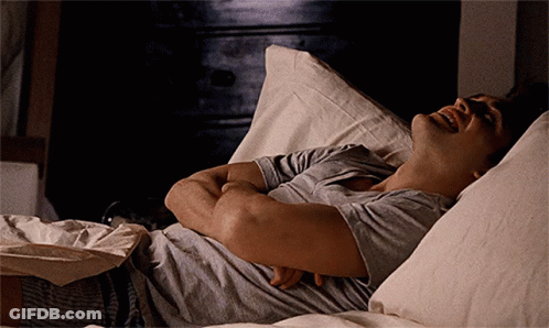 A Man Laying On A Bed With His Arms Crossed And His Mouth Open GIF