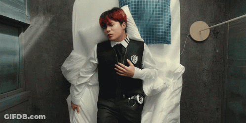 A Man Laying On A Bed With His Hand On His Chest GIF