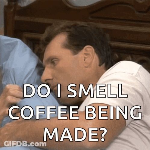 A Man Laying On A Bed With The Words " Do I Smell Coffee Being Made " Above Him GIF