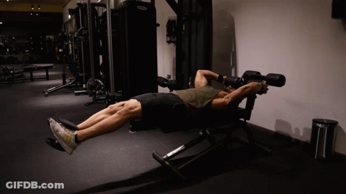 A Man Laying On A Bench In A Gym With A Machine That Says Technogym On It GIF