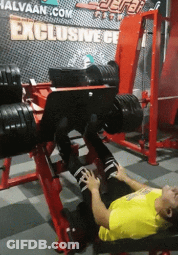 A Man Laying On A Bench In A Gym With A Sign That Says Exclusive GIF