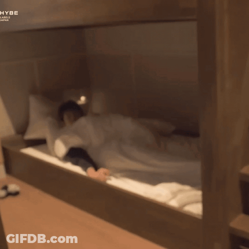 A Man Laying On A Bunk Bed With The Word Hybe On The Bottom Right GIF