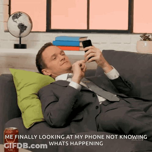 A Man Laying On A Couch Looking At His Phone GIF