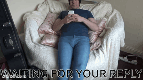A Man Laying On A Couch With The Words Waiting For Your Reply Below Him GIF