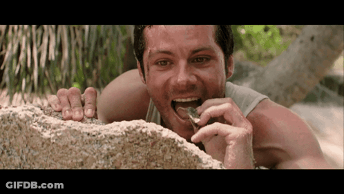 A Man Laying On A Rock Eating Something GIF
