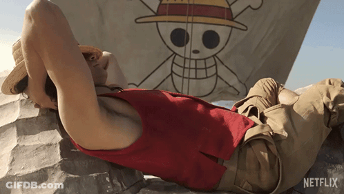 A Man Laying On A Rock In Front Of A Netflix Flag GIF