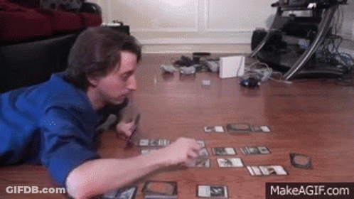 A Man Laying On The Floor Playing A Game Of Cards GIF