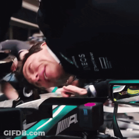 A Man Laying On Top Of A Green Car With The Word Amg On The Side GIF