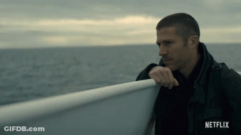 A Man Leaning Against A Railing On A Boat With Netflix Written On The Bottom GIF