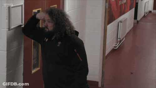 A Man Leaning Against A Wall In A Hallway With Bbc Written On The Corner GIF