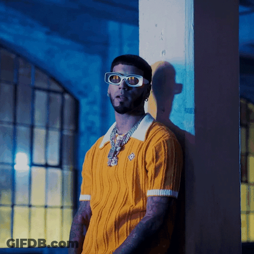 A Man Leaning Against A Wall Wearing Sunglasses GIF