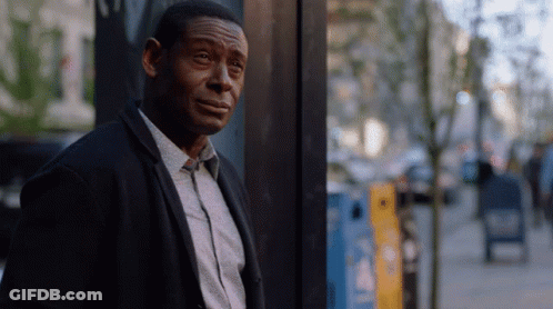 A Man Leaning Against A Wall With A Yellow Box In The Background That Says ' A ' On It GIF