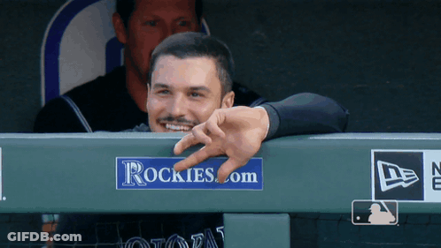 A Man Leaning Over A Rockies.com Sign GIF