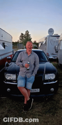 A Man Leans Against A Black Car With A License Plate That Says ' 6060 ' GIF