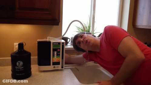 A Man Leans Over A Sink Next To A Bottle Of Energe GIF