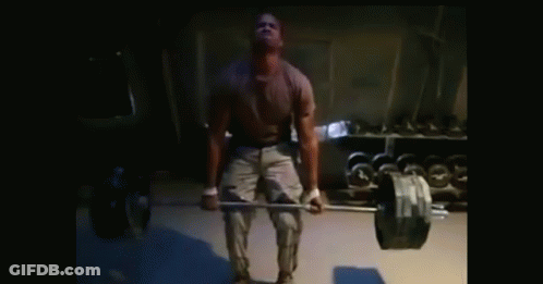 A Man Lifts A Barbell In A Dark Room GIF