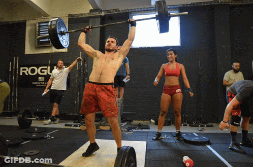 A Man Lifts A Barbell Over His Head In Front Of A Rogue Sign GIF