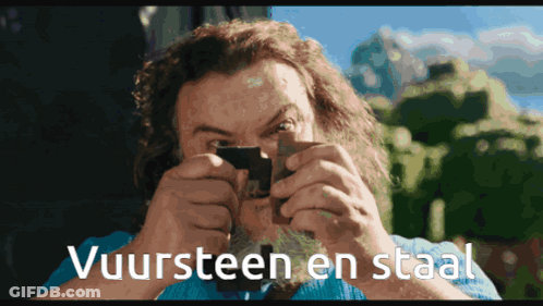 A Man Looking Through A Magnifying Glass With The Words Vuursteen En Staal Written Below Him GIF