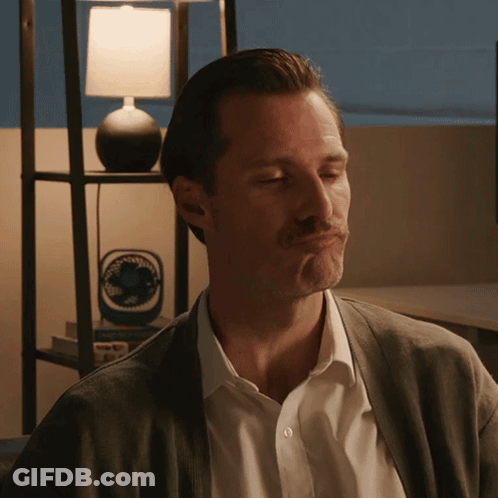A Man Making A Face In Front Of A Lamp And A Fan GIF