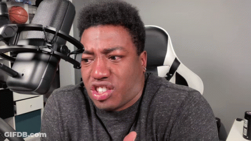 A Man Making A Funny Face In Front Of A Microphone With A Basketball On The Wall Behind Him GIF