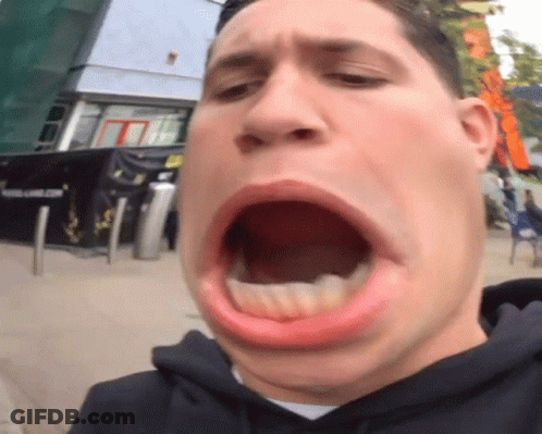 A Man Making A Funny Face With His Mouth Open In Front Of A Building That Says Young Game.com GIF